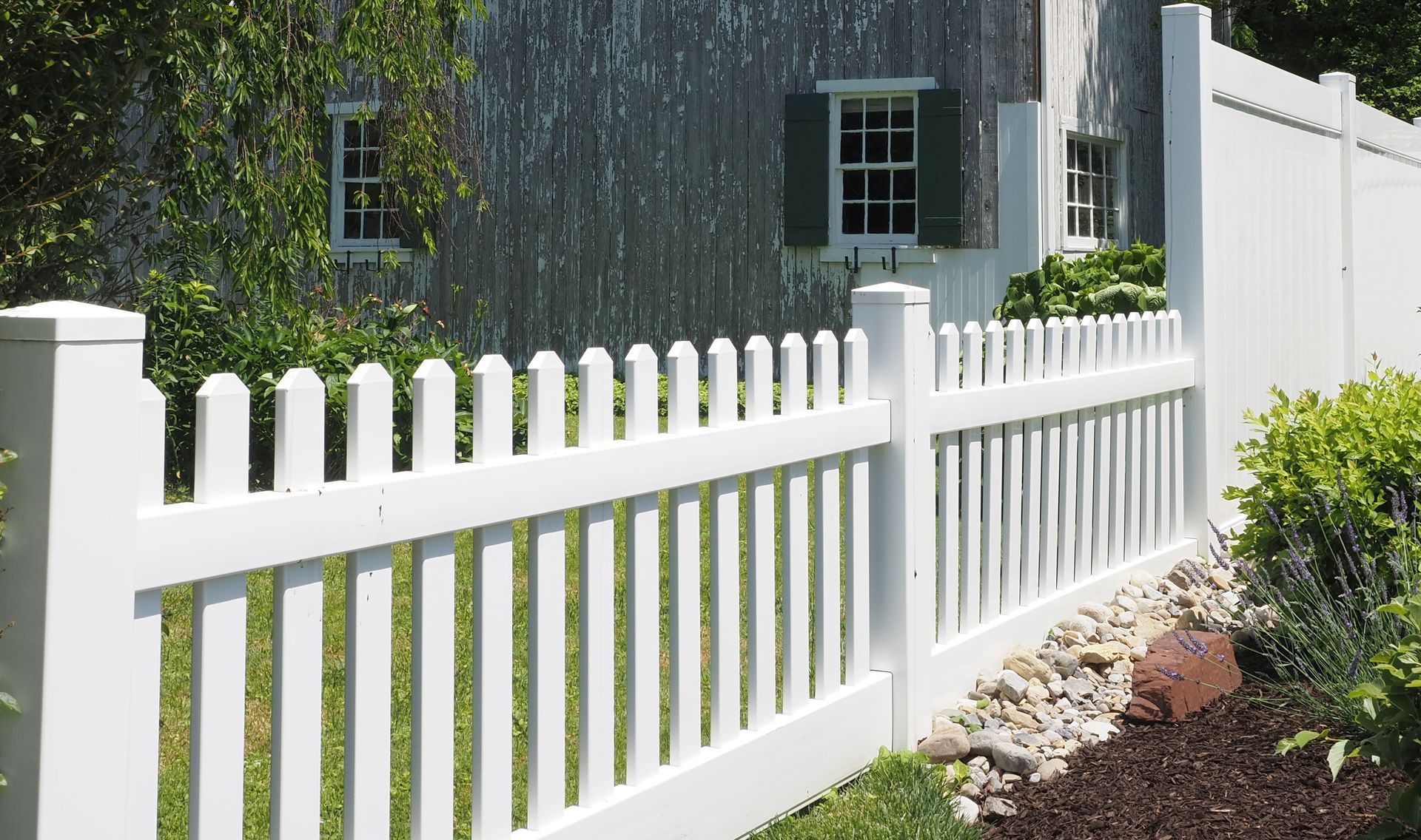 Rustic barn with white picket fence and lush greenery in Doylestown, PA.