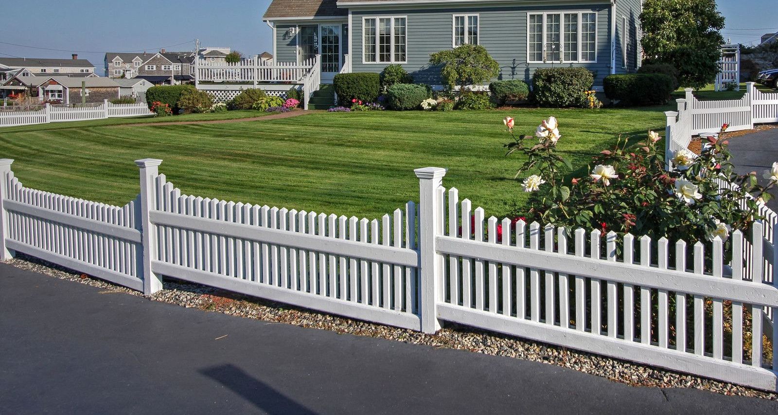 A picturesque New England home with white picket fence and manicured lawn, perfect for residential living.